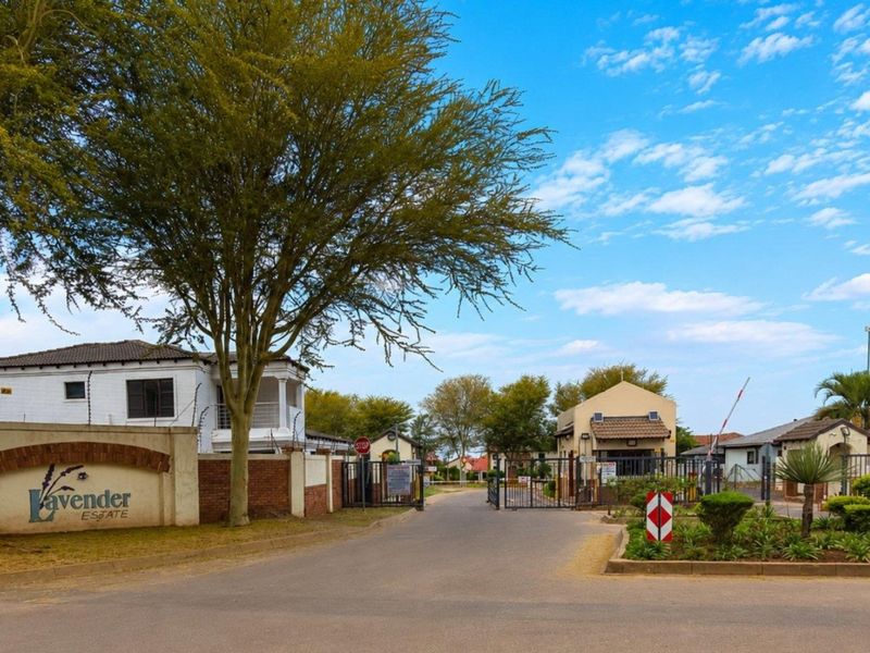 Entrance view of Lavender Estate featuring a secure gated access point, perimeter walling with electric fencing, and a paved approach road.
