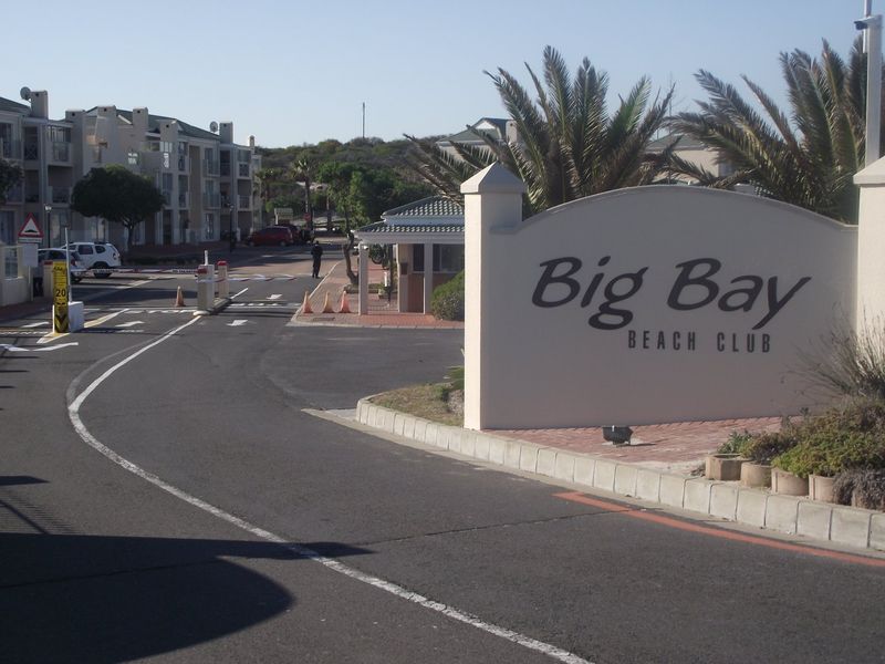 Entrance view of the Big Bay Beach Club complex featuring a security gatehouse, boom gate access, and paved road infrastructure.