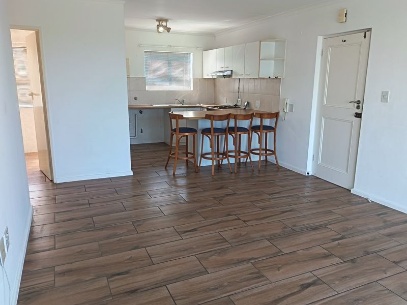 Open-plan living and kitchen area featuring wood-look tiled flooring, built-in cabinetry, and a breakfast bar counter.
