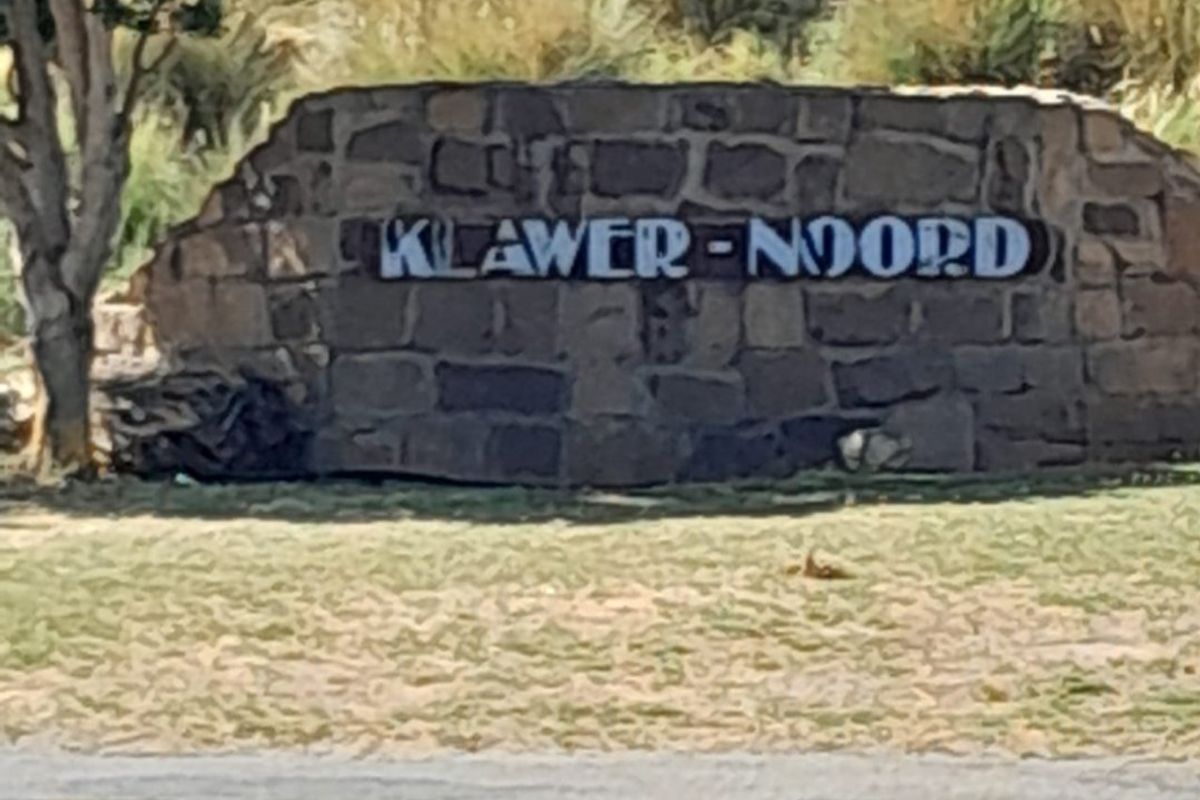 A stone signage wall marking the entrance to Klawer-Noord, situated along a paved roadside.