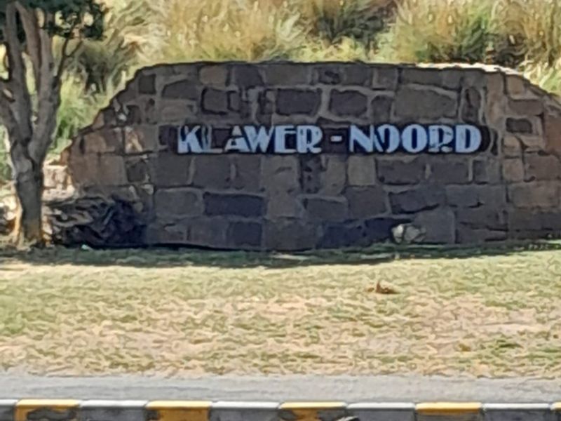 A stone signage wall marking the entrance to Klawer-Noord, situated along a paved roadside.