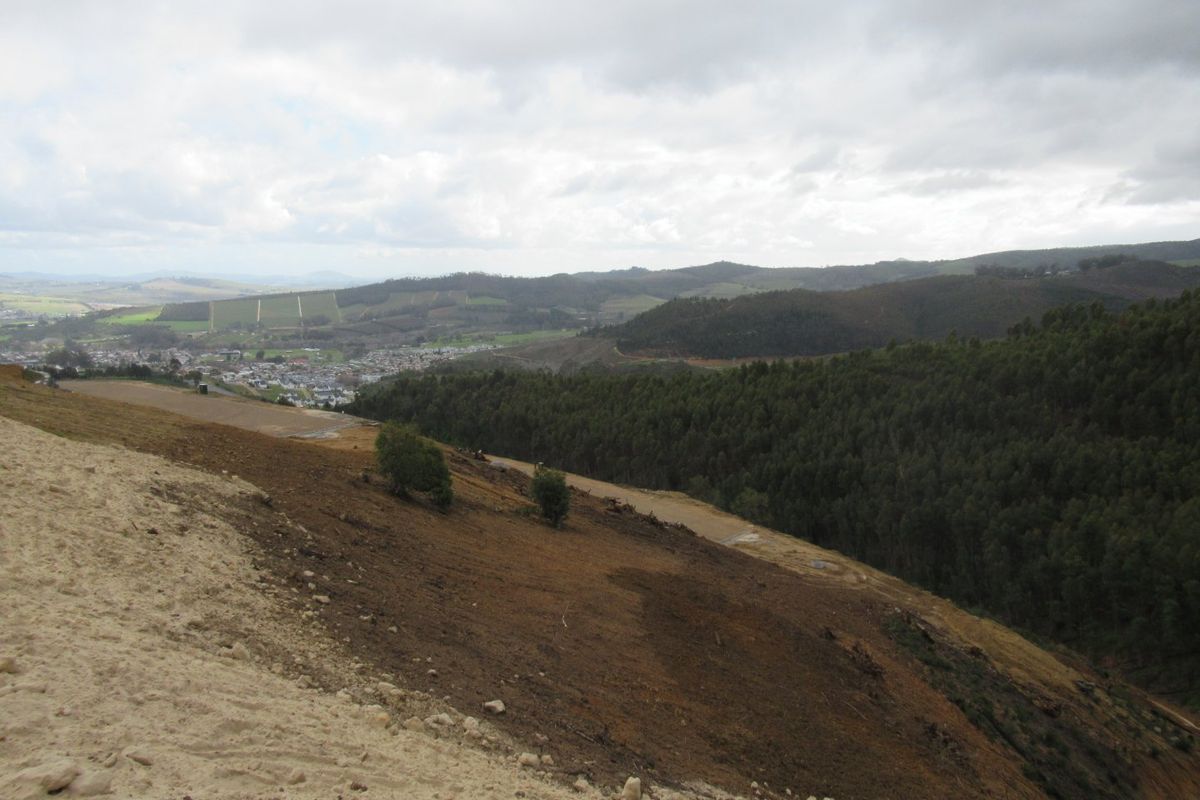 Expansive elevated view overlooking rolling hills, forested areas, and a distant town, showcasing the natural landscape and topography of the vacant land.