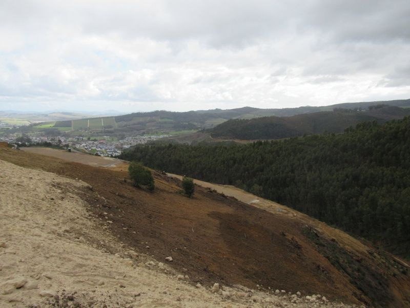 Expansive elevated view overlooking rolling hills, forested areas, and a distant town, showcasing the natural landscape and topography of the vacant land.