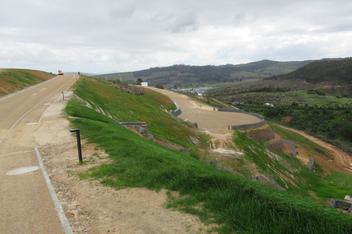 An elevated view of a residential development site featuring paved roads, landscaped embankments, and stone retaining walls overlooking a valley.