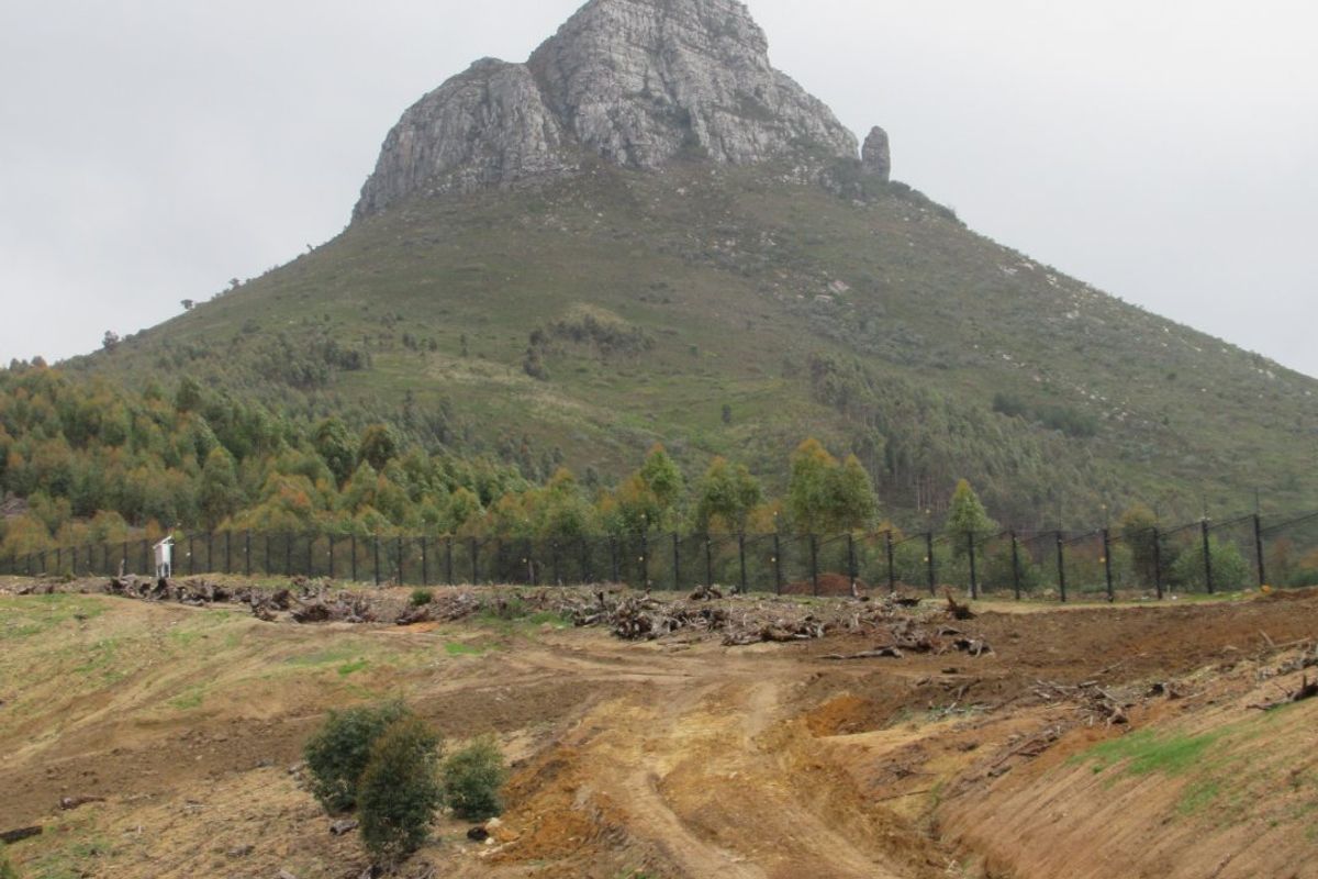 A view of the vacant residential land featuring a prominent mountain backdrop and perimeter fencing.