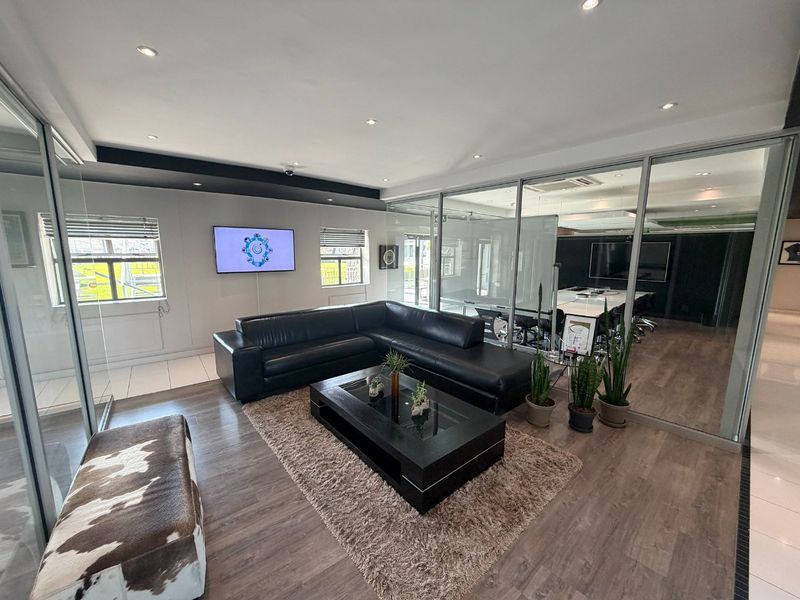 Modern commercial office space featuring glass partition walls, recessed lighting, and laminate flooring, creating a professional and open work environment.