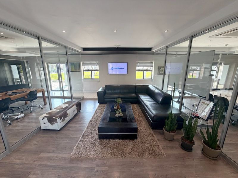 Modern commercial office space featuring glass partition walls, recessed lighting, and high-quality laminate flooring, creating a professional and open work environment.