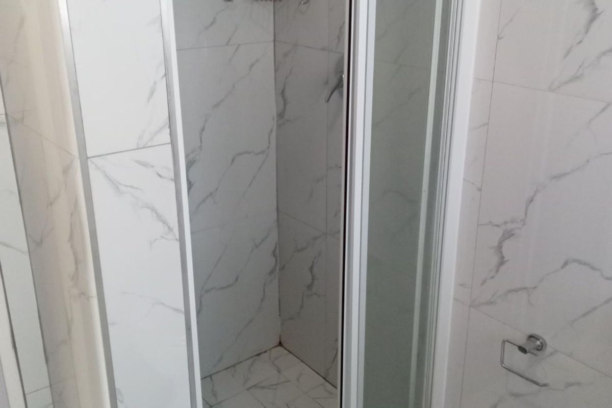 A modern bathroom featuring a glass-enclosed shower with marble-look wall and floor tiles.