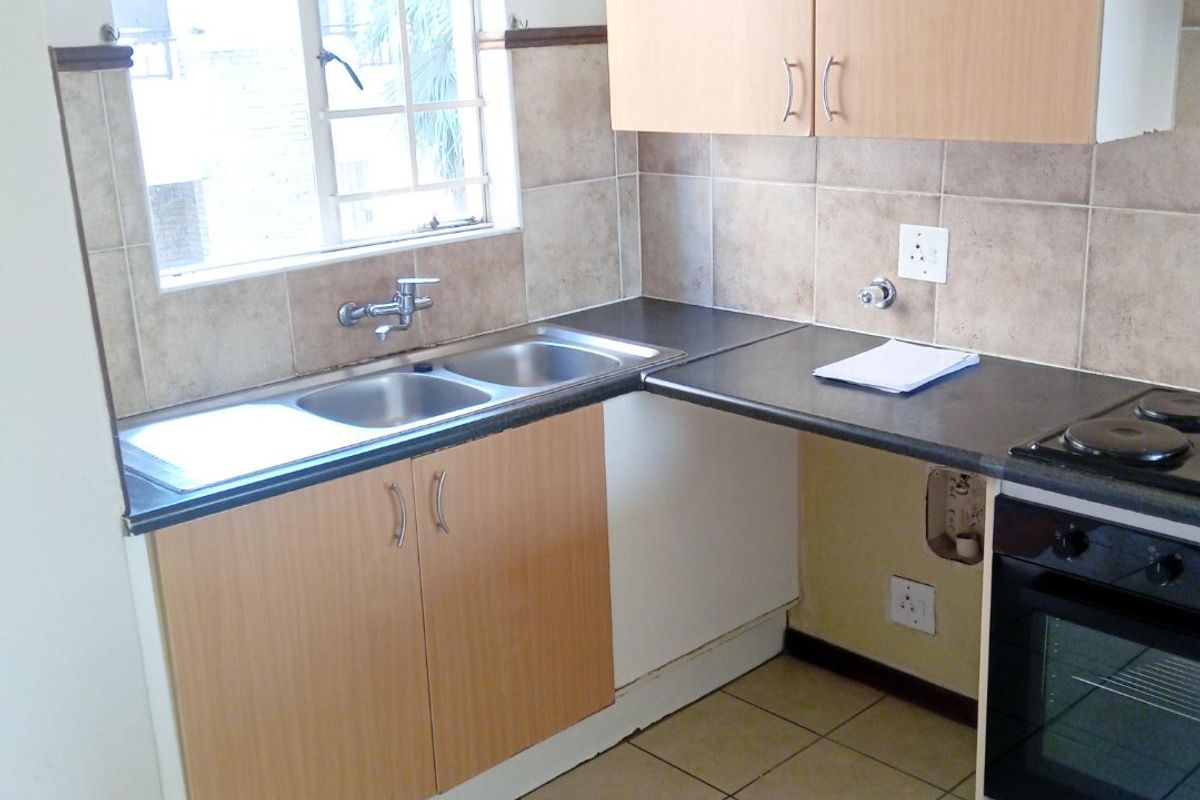 Functional kitchen featuring laminate cabinetry, double bowl sink, built-in oven, electric hob, and ceramic tile finishes throughout.