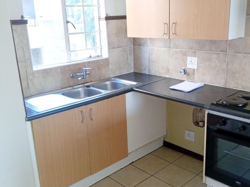 Functional kitchen featuring laminate cabinetry, double bowl sink, built-in oven, electric hob, and ceramic tile finishes throughout.