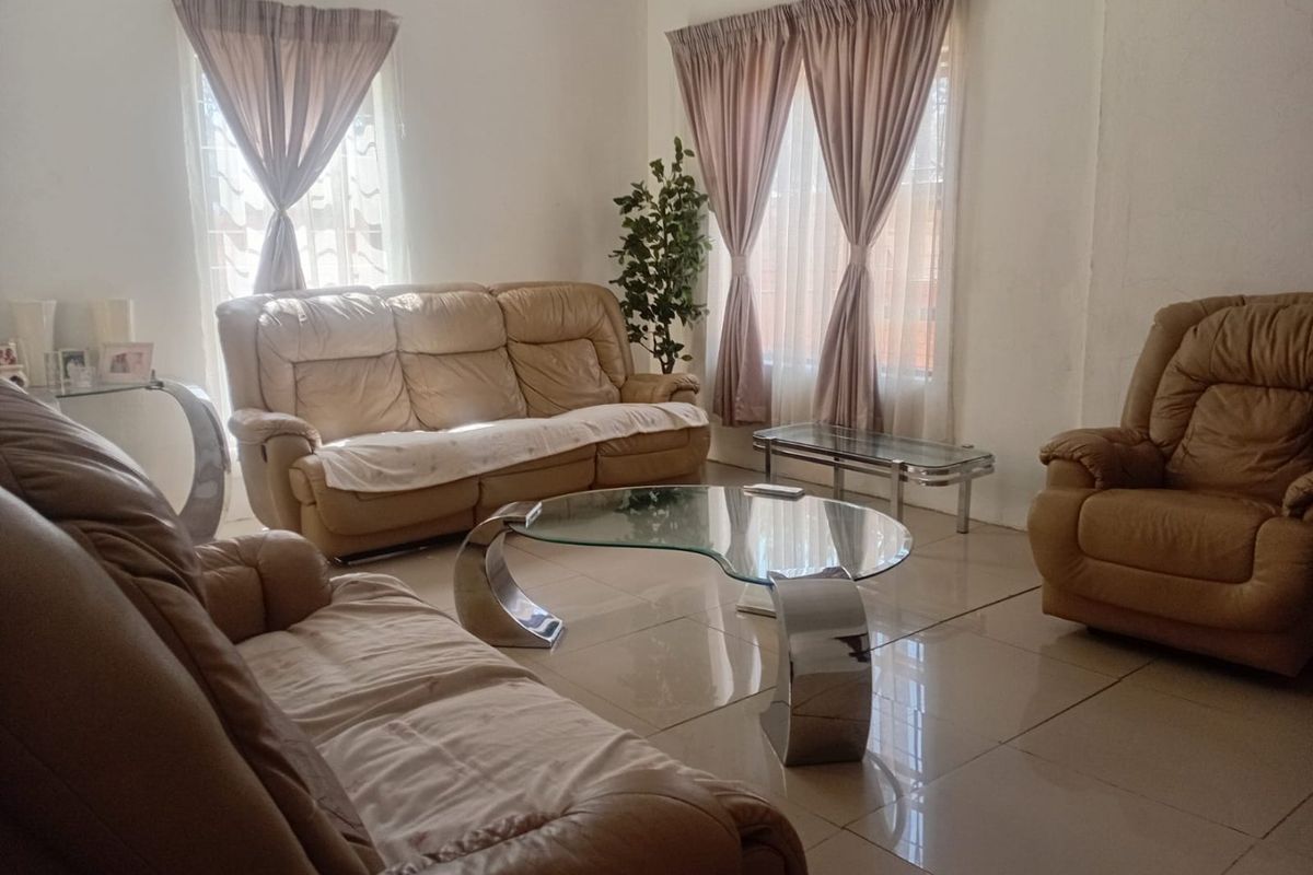 A bright living room featuring neutral tiled flooring and large windows with installed curtain rails, offering a clean and functional space.