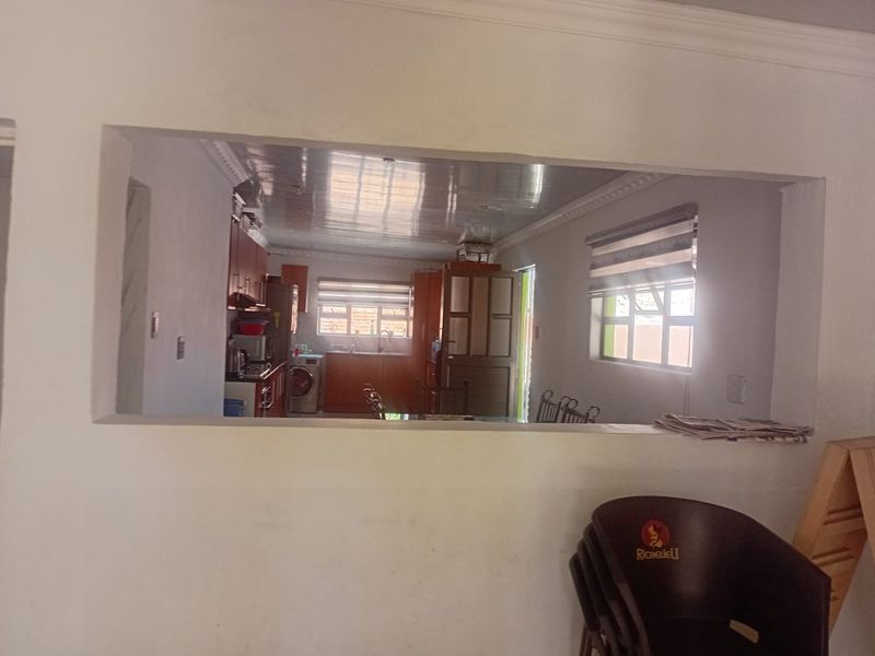 An open-plan kitchen area viewed through a pass-through window, featuring built-in cabinetry and functional workspace.