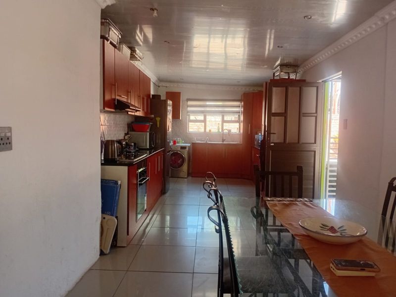 Open-plan kitchen and dining area featuring tiled flooring, built-in cabinetry, and integrated appliances, offering a functional layout for daily living.