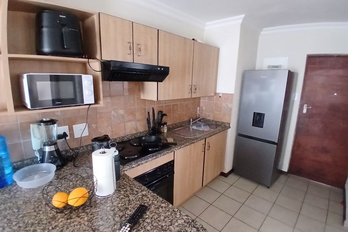Functional kitchen featuring laminate cabinetry, granite countertops, built-in oven, electric hob, extractor fan, and tiled flooring.