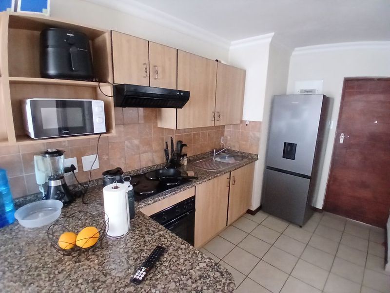 Functional kitchen featuring laminate cabinetry, granite countertops, built-in oven, electric hob, extractor fan, and tiled flooring.