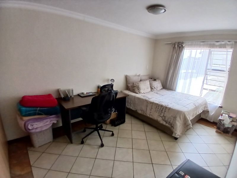A functional bedroom featuring tiled flooring, coved ceilings, and a large window allowing natural light into the space.