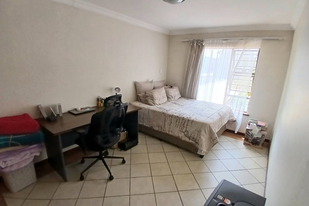 A functional bedroom featuring tiled flooring, a window with security bars, and a ceiling-mounted light fixture.