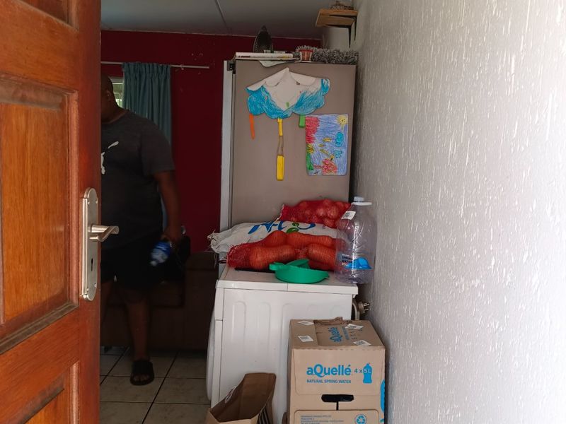 A small utility or laundry area featuring tiled flooring and textured wall finishes, currently used for storage.