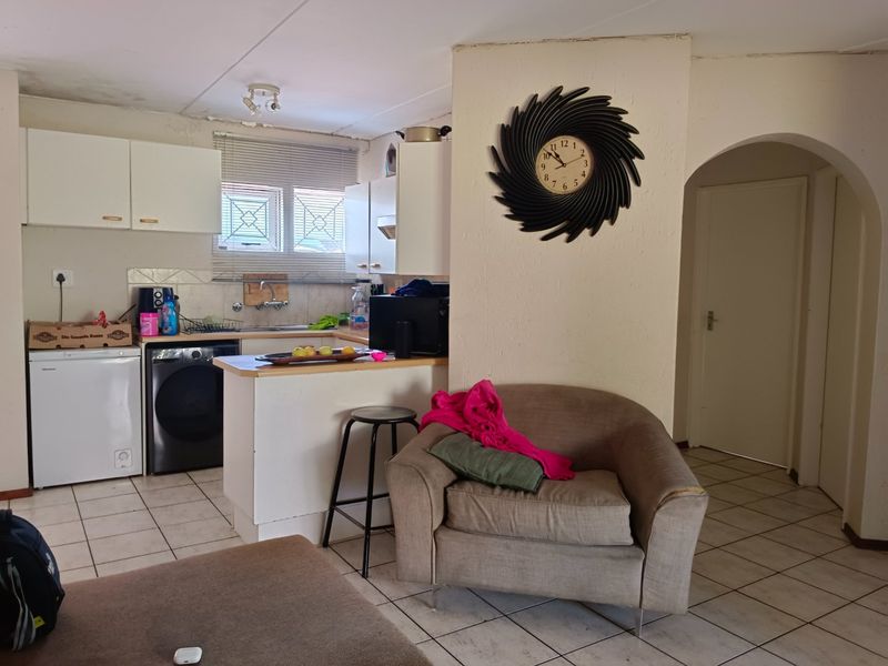 Open plan kitchen and living area featuring tiled flooring, built-in cabinetry, and an arched doorway leading to other parts of the apartment.