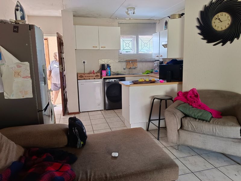 Open-plan living and kitchen area featuring tiled flooring and functional cabinetry, requiring cosmetic updates to improve the overall aesthetic and condition.