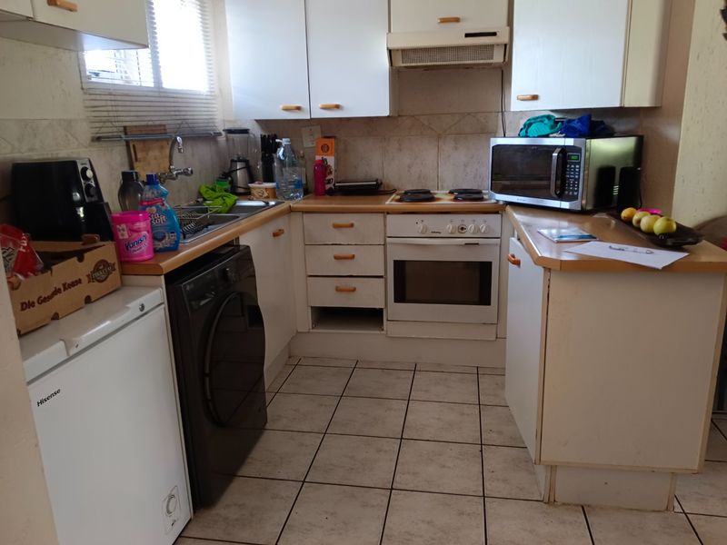 Compact kitchen featuring built-in cabinetry, laminate countertops, a built-in oven with hob, and tiled flooring. The space offers functional storage and preparation areas.