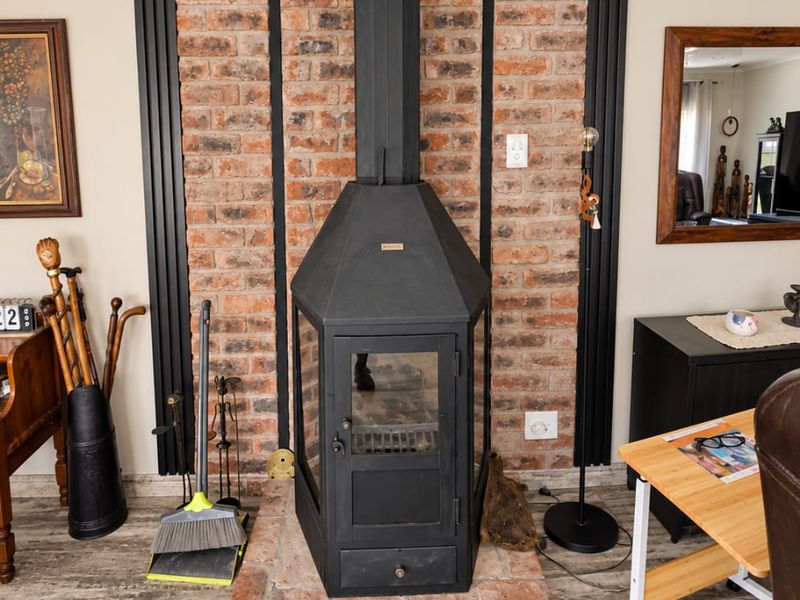 A living room featuring a prominent brick feature wall with a black freestanding fireplace and durable laminate flooring.