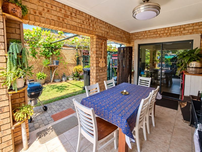 A covered outdoor patio area featuring brick pillars, tiled flooring, and direct access to the interior through sliding glass doors.