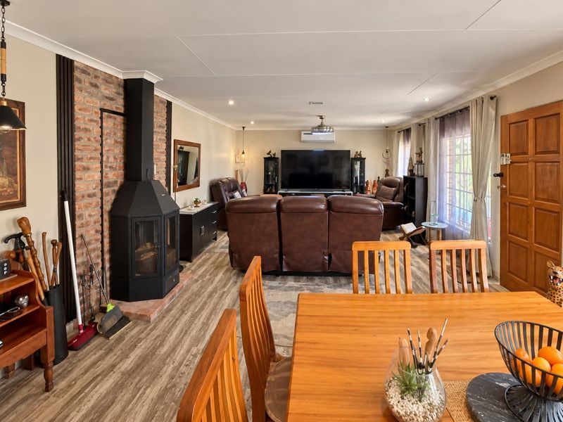 Spacious open-plan living and dining area featuring a prominent brick fireplace, modern laminate flooring, and integrated climate control.