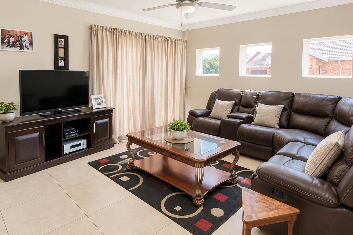 A well-maintained living room featuring neutral tiled flooring, a ceiling fan, and sliding glass doors that provide access to the outdoor area.