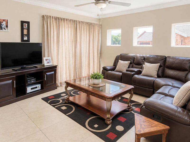 A well-maintained living room featuring neutral tiled flooring, a ceiling fan, and sliding glass doors that provide access to the outdoor area.