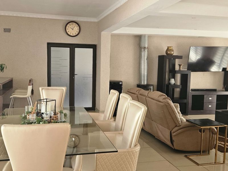 Spacious open-plan living and dining area featuring tiled flooring, crown molding, a fireplace, and neutral wall finishes.