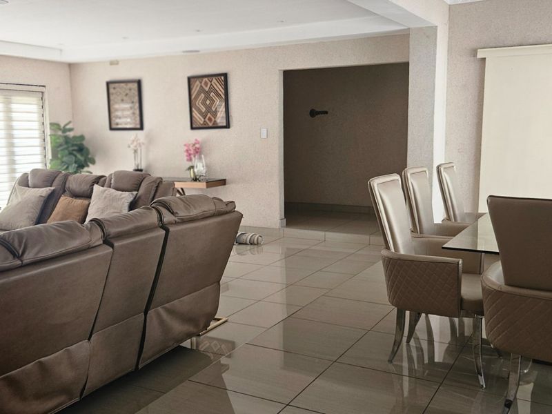 Spacious open-plan living and dining area featuring large format floor tiles, recessed lighting, and a sliding door leading to the exterior.