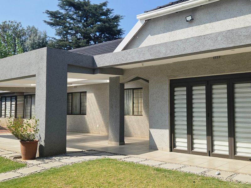 A spacious covered patio area featuring tiled flooring and modern folding glass doors, providing seamless access to the garden.
