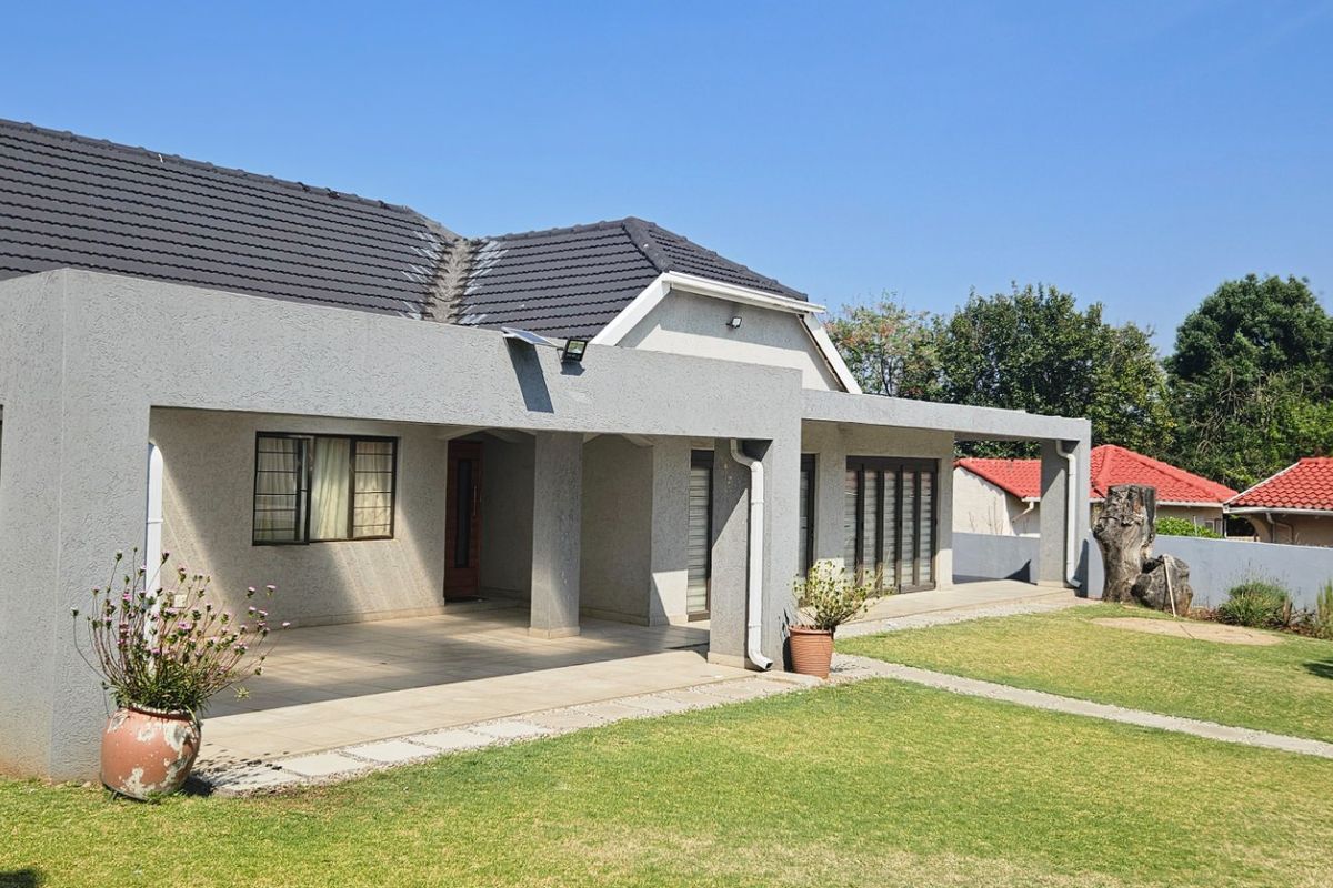 Spacious rear exterior featuring a large covered patio with tiled flooring, overlooking a well-maintained garden and lawn area.