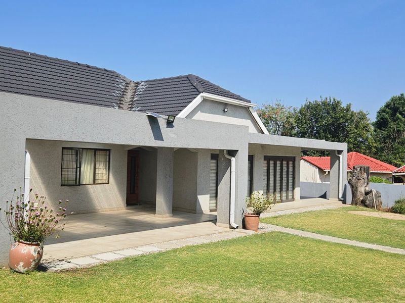 Spacious rear exterior featuring a large covered patio with tiled flooring, overlooking a well-maintained garden and lawn area.