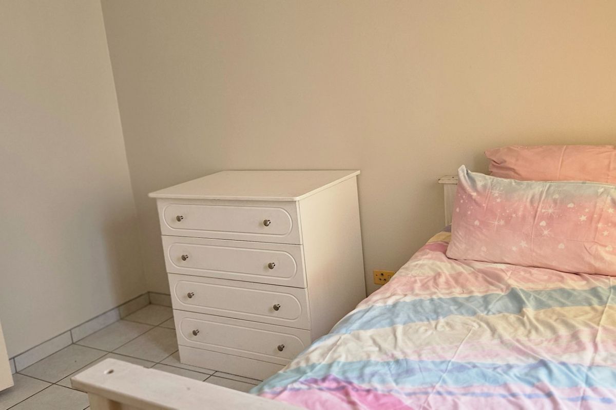 A simple bedroom featuring tiled flooring and neutral wall finishes, providing a functional space for a single bed.