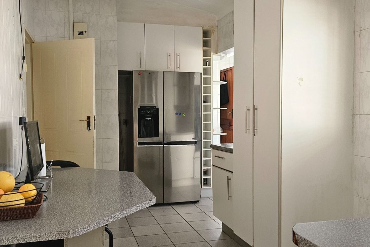 A functional kitchen featuring tiled walls and flooring, ample built-in cabinetry, and laminate countertops, providing a practical workspace for daily meal preparation.