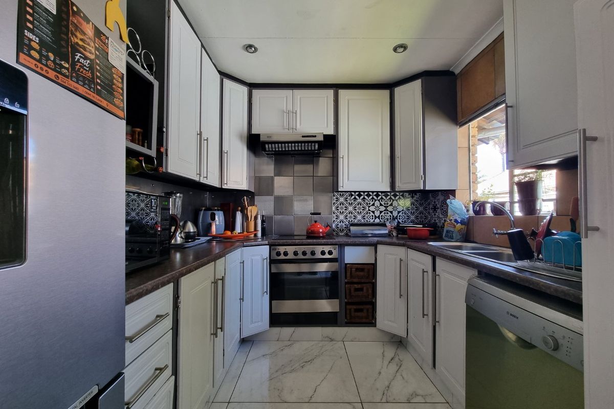 A functional kitchen featuring modern white cabinetry, stainless steel appliances, a tiled backsplash, and marble-look floor tiles.