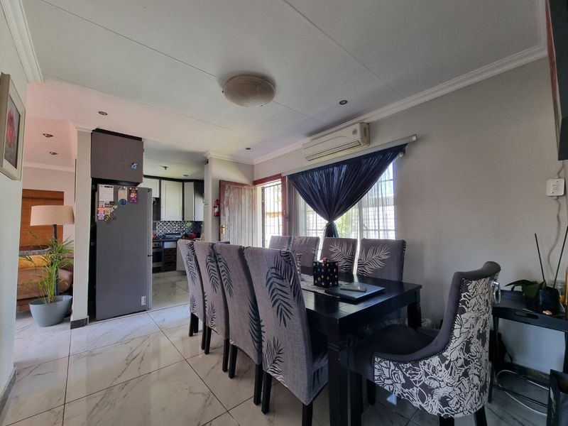 Open-plan dining area featuring tiled floors and a split-system air conditioner, with a view into the adjacent kitchen space.