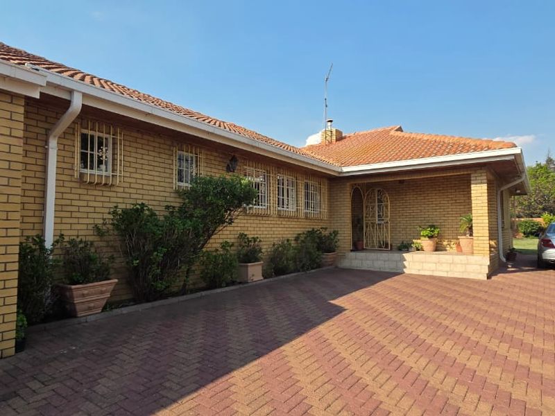 Front elevation of a face brick house featuring a tiled roof, paved driveway, and secure window treatments.