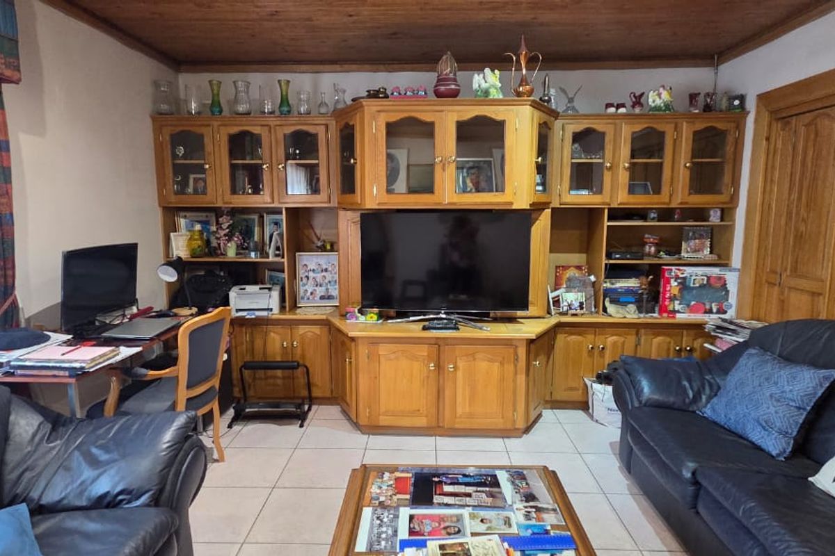 A living room featuring built-in wooden cabinetry, tiled flooring, and a timber ceiling, offering a functional space with integrated storage.