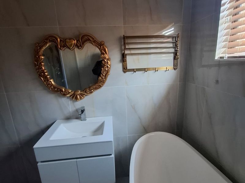 Modern bathroom featuring a wall-mounted vanity, a sleek freestanding bathtub, and floor-to-ceiling marble-look wall tiles.