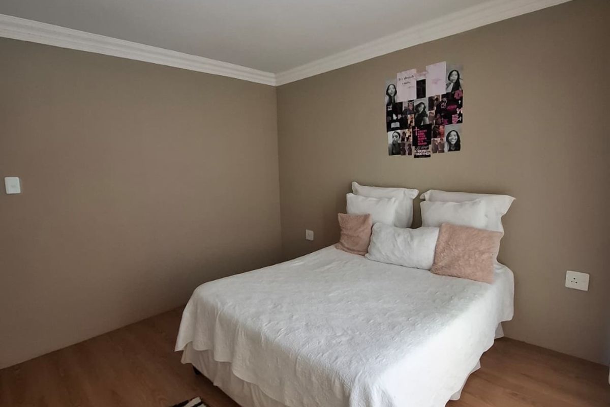 A well-maintained bedroom featuring laminate flooring, coving, and neutral wall tones, providing a clean and functional living space.