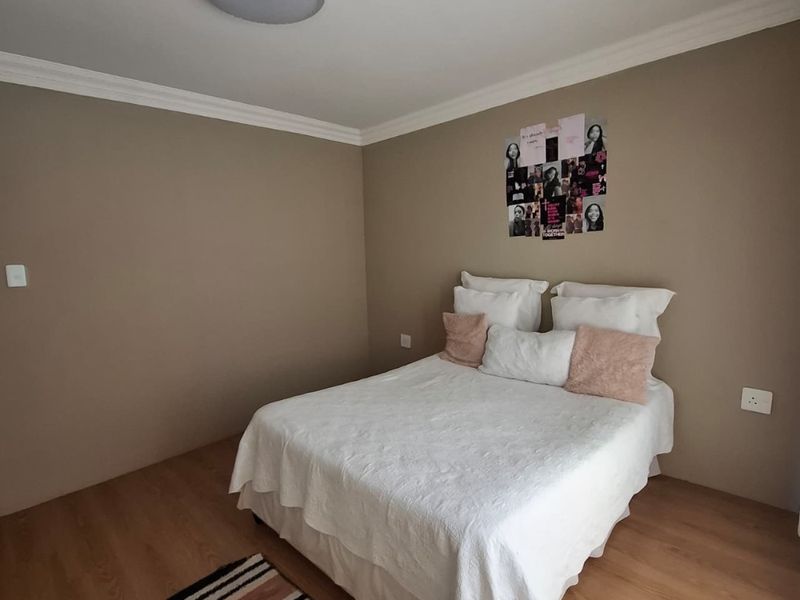 A well-maintained bedroom featuring laminate flooring, coving, and neutral wall tones, providing a clean and functional living space.