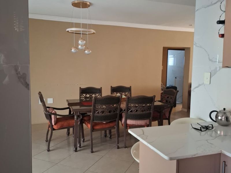 Open-plan dining area featuring tiled flooring, recessed ceiling lighting, and a modern marble-look kitchen countertop, creating a functional and connected living space.