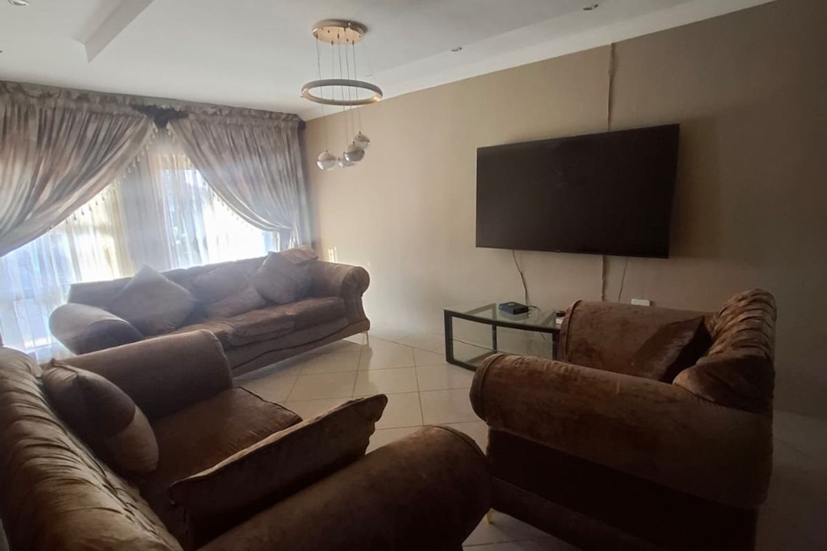A living room featuring tiled flooring, a recessed ceiling design, and a wall-mounted television.