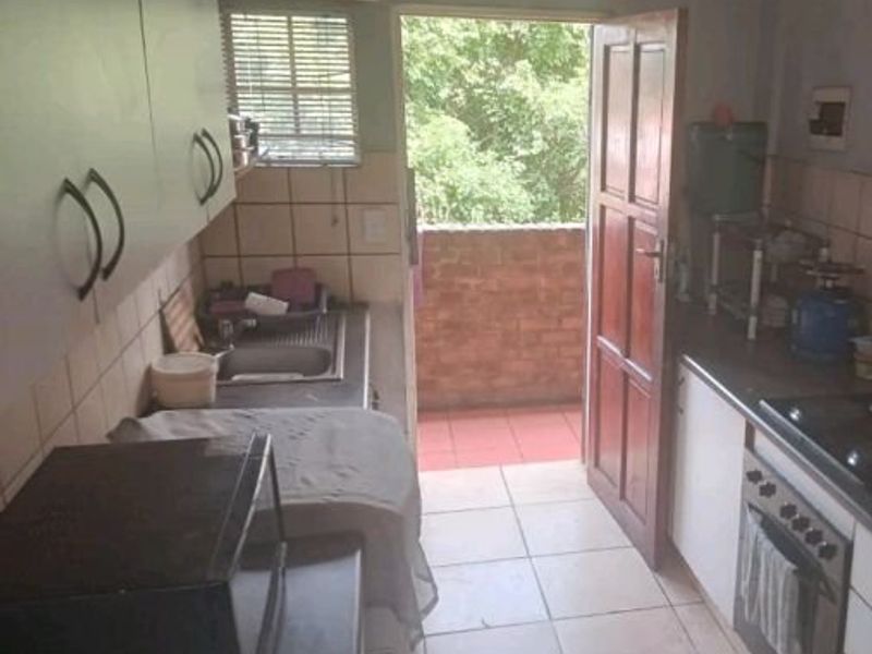 Functional kitchen featuring built-in cabinetry, oven, hob, and tiled finishes, with direct access to an outdoor balcony area.