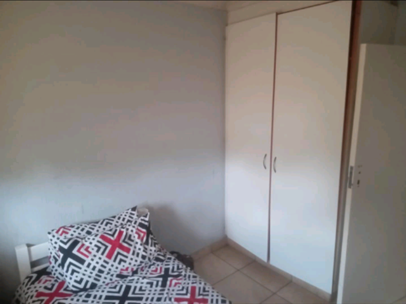 A bedroom featuring tiled flooring and a built-in wardrobe with white doors.