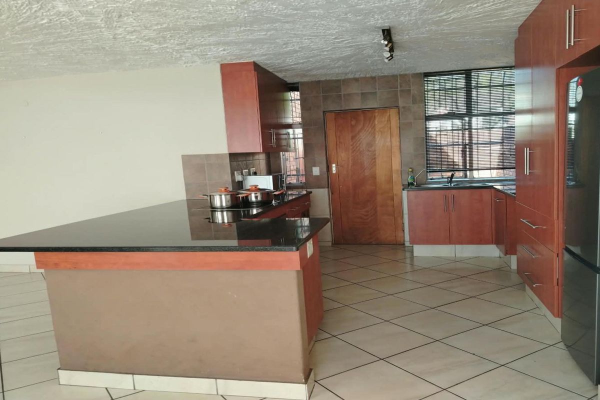 A functional kitchen featuring granite countertops, ample built-in cabinetry, tiled flooring, and a tiled backsplash, offering a practical layout for daily meal preparation.