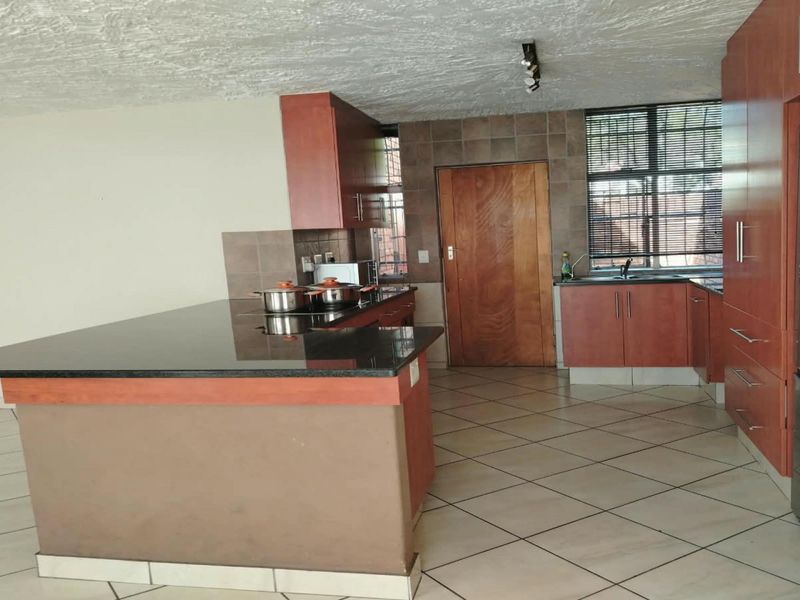 A functional kitchen featuring granite countertops, ample built-in cabinetry, tiled flooring, and a tiled backsplash, offering a practical layout for daily meal preparation.